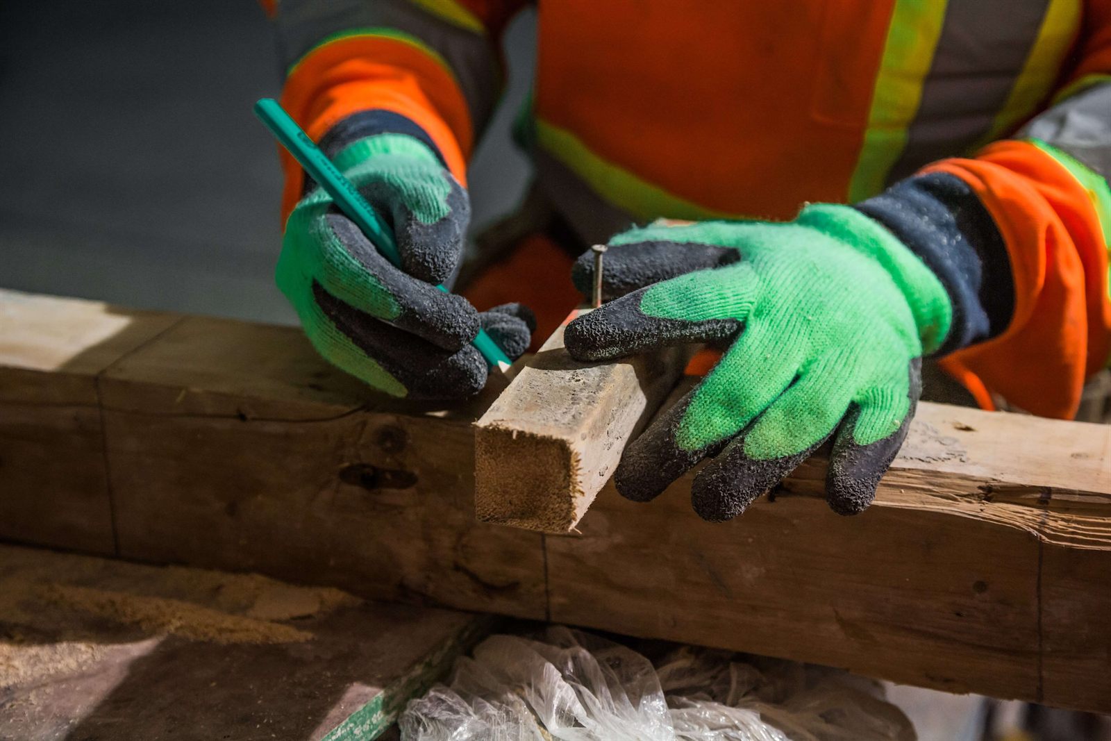 Constructor măsurând cu atenție o piesă de lemn pe șantier